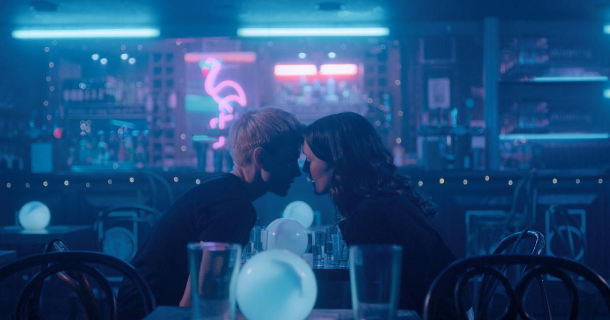 le due protagoniste stanno per baciarsi tra le luci blu di un locale - nerdface