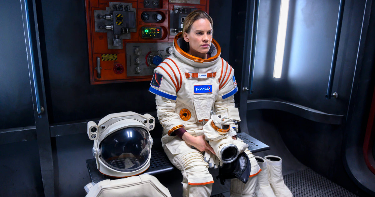 hillary swank è seduta su una, col casco della tuta spaziale al suo fianco. sta probabilmente concentrandosi in vista del lungo viaggio verso marte - nerdface