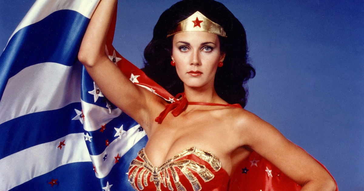 lynda carter nella celebre posa di wonder woman che tiene la bandiera americana - nerdface