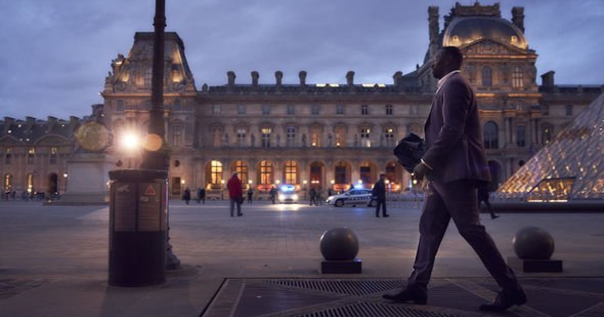 omar sy cammina sornione all'esterno del louvre, la sera - nerdface