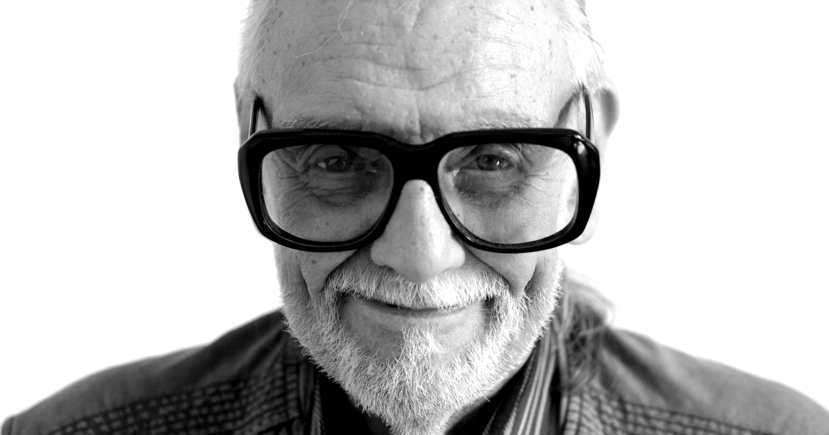 george a. romero guarda in camera e sorride e indossa un paio di occhiali da vista enormi - nerdface