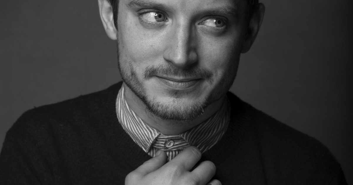 elijah wood in una posa divertente, in cui fa una smorfia e si tiene il colletto della camicia - nerdface