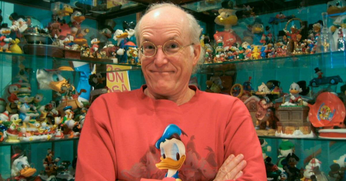 don rosa sorride davanti alla collezione di paperi - nerdface