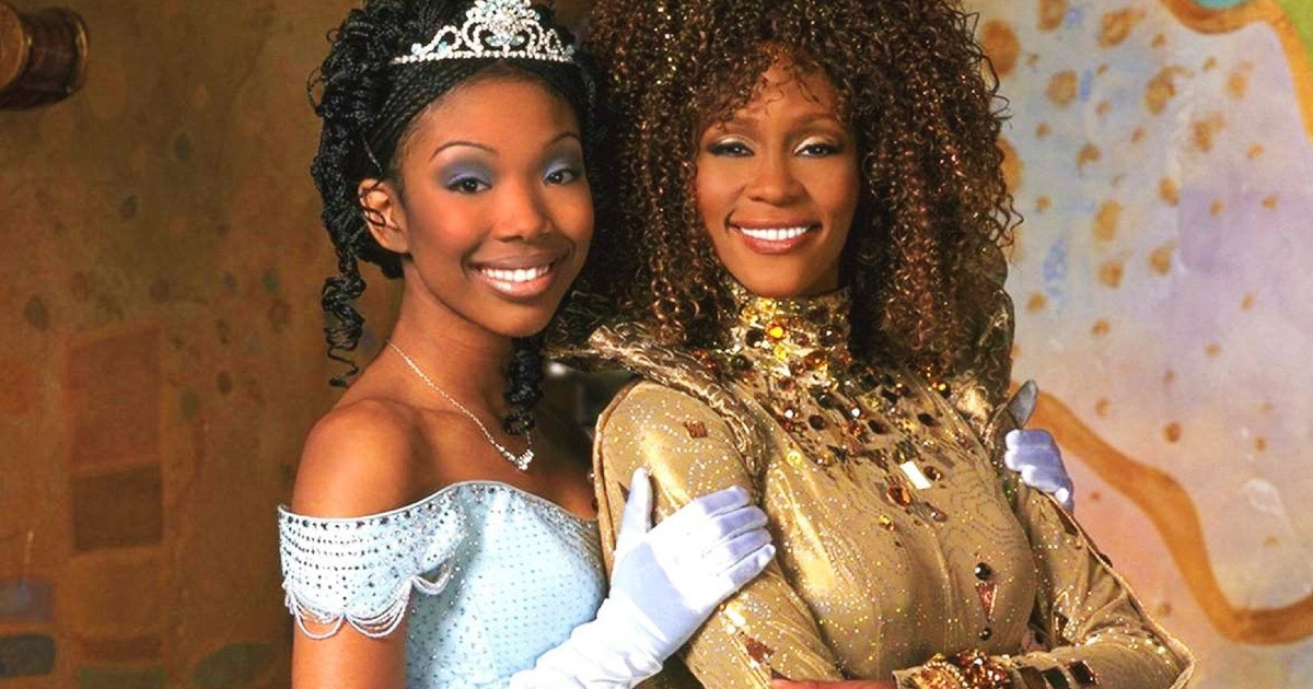 In Cenerentola di Rodgers e Hammerstein, Brandy, che interpreta Cenerentola, abbraccia Whitney Houston vestita in oro. entrambe sorridono.