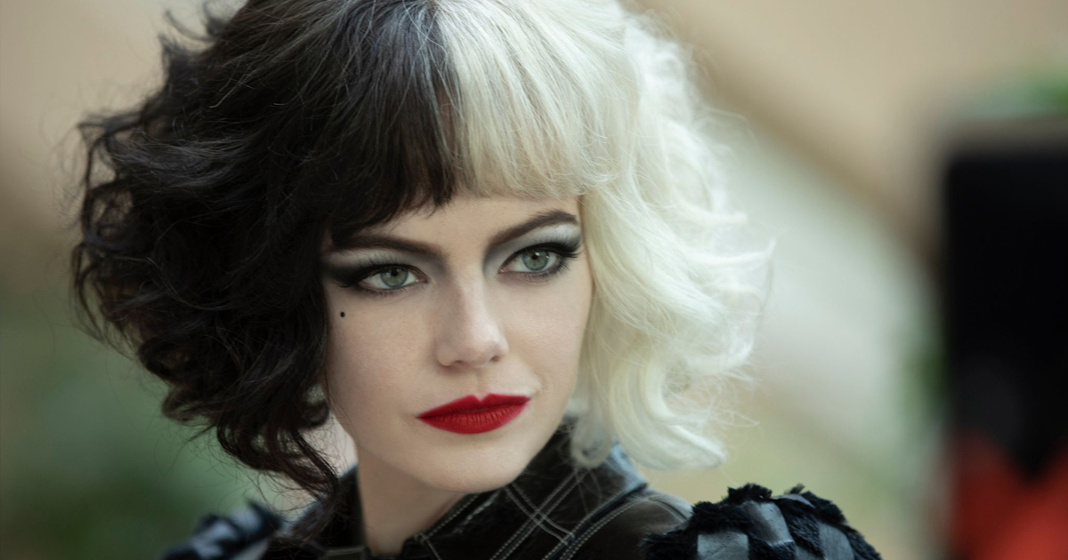 Un primo piano di Emma Stone, che interpreta Crudelia. Sguardo intenso, labbra rosso fuoco, capelli metà bianchi e metà neri con la frangetta.