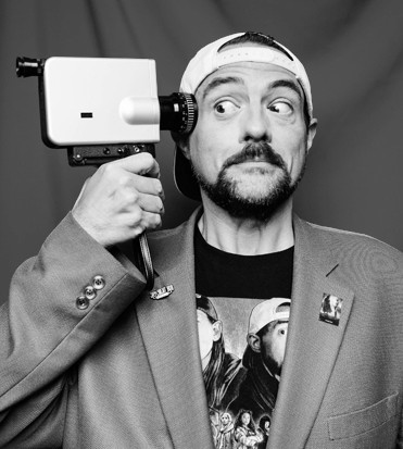 primo piano di kevin smith con una videocamera puntata alla tempia - nerdface