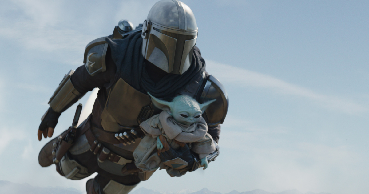 il mandalorian è in volo e tiene in braccio baby yoda - nerdface