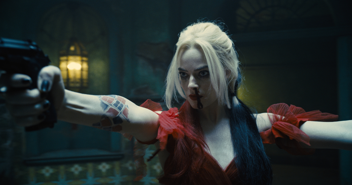 margot robbie è harley quinn, imndossa un abito rosso e punta la pistola contro qualcuno - nerdface