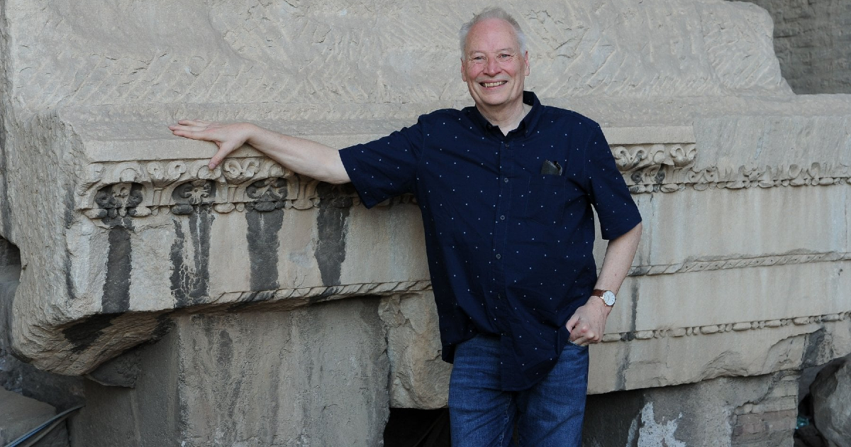 lo scrittore sorride mentre è a roma, poggiato su un rudere - nerdface