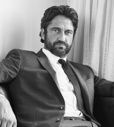 un ritratto in bianco e nero di gerard butler in giacca e cravatta seduto su una poltrona - nerdface