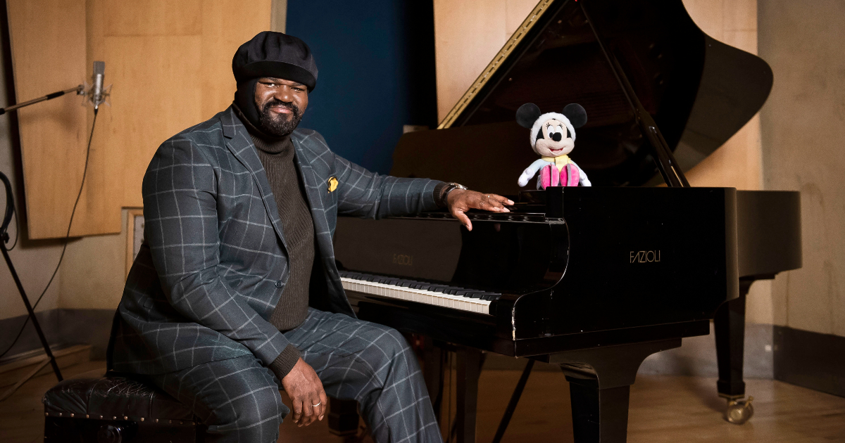 gregory porter seduto al piano a coda accanto al pupazzo di minnie - nerdface