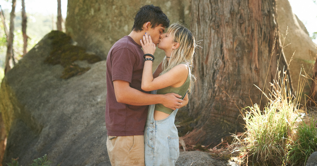 due giovani si baciano davanti un grande albero - nerdface