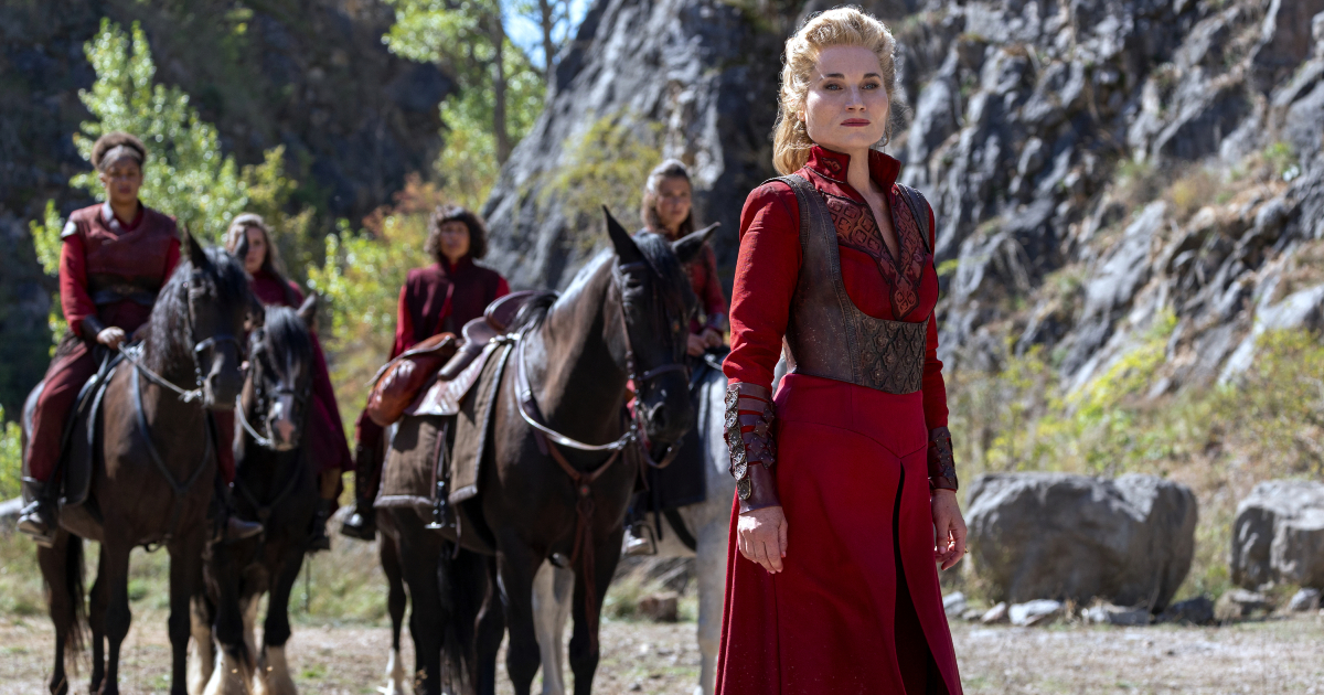 una donna in abito rosso guida un gruppo a cavallo - nerdface