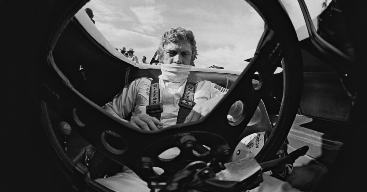 una foto dall'interno della vettura da corsa mostra uno steve mcqueen concentrato al volante - nerdface