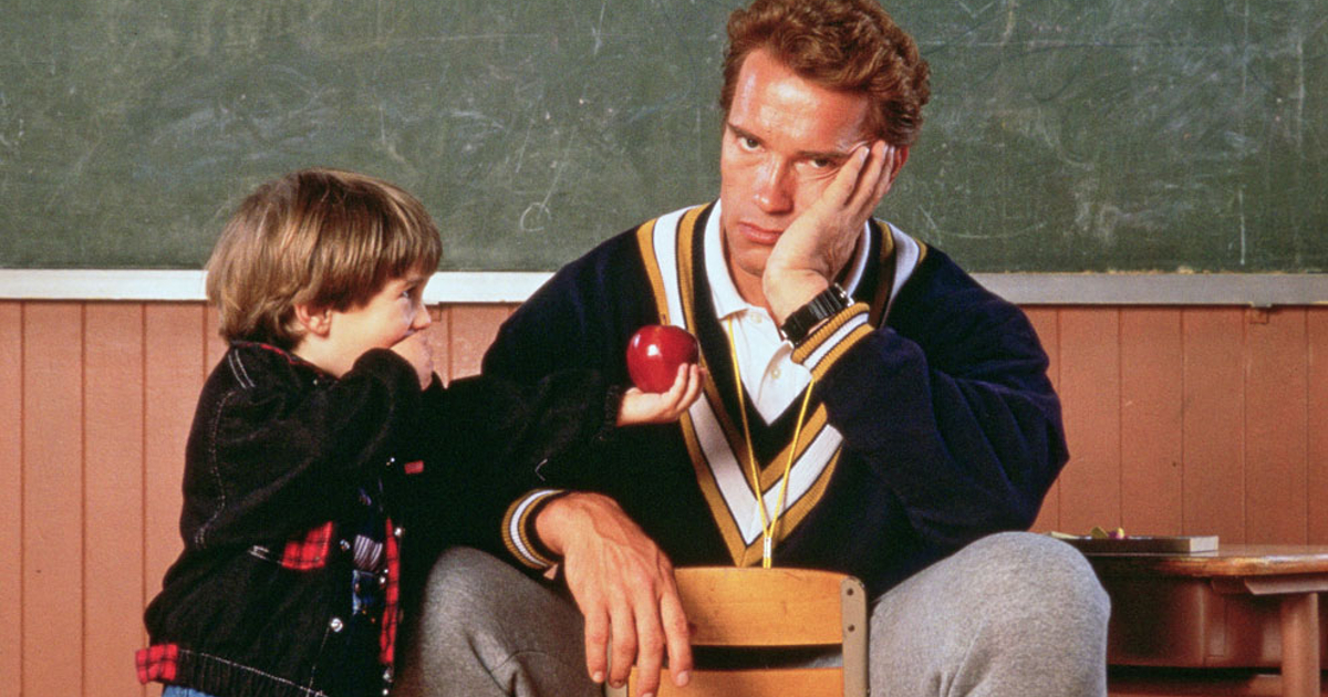 un bambino porge una pallina rossa ad arnoldone, ma lui proprio non ce la fa più in kindergarten cop - nerdface