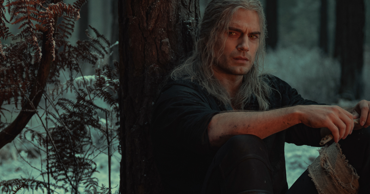 geralt è poggiato con la schiena su un albero e guarda qualcuno nella seconda stagione di the witcher - nerdface