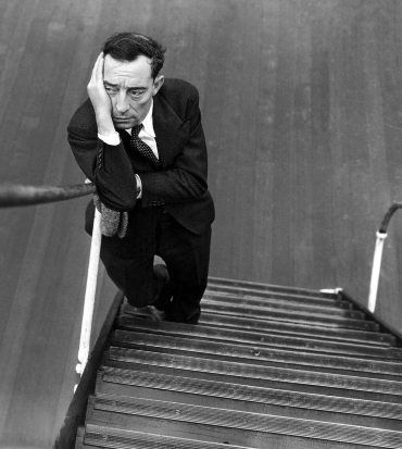 buster keaton è poggiato sulla balaustra di una scala e si tiene la testa con la mano - nerdface