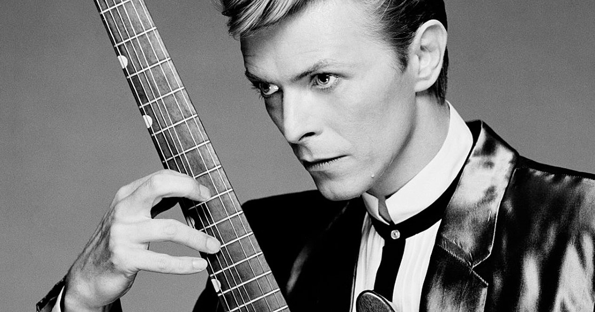 david bowie in bianco nero tiene in mano una chitarra - nerdface