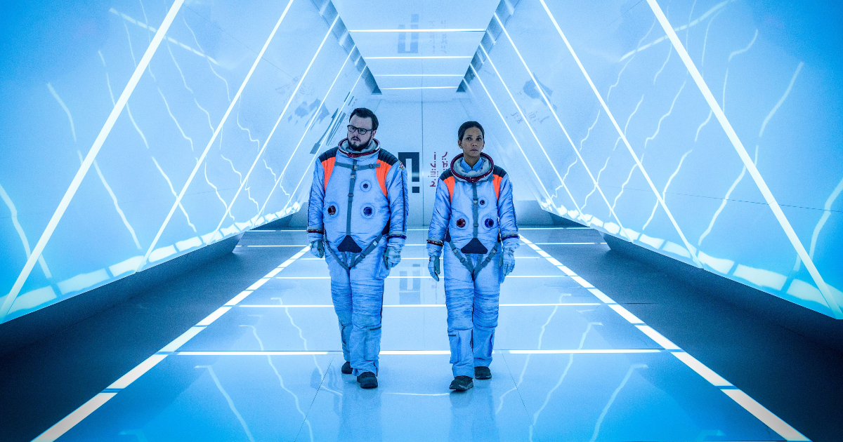 due protagonisti nel trailer di Moonfall, diretto da Roland Emmerich, camminano in un corridoio - nerdface