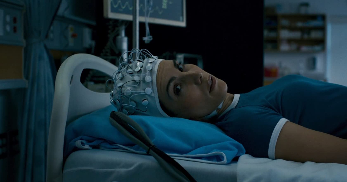 la protagonista è stesa a letto e indossa il casco pieno di elettrodi che le permetterà di entrare nella mente della madre - nerdface