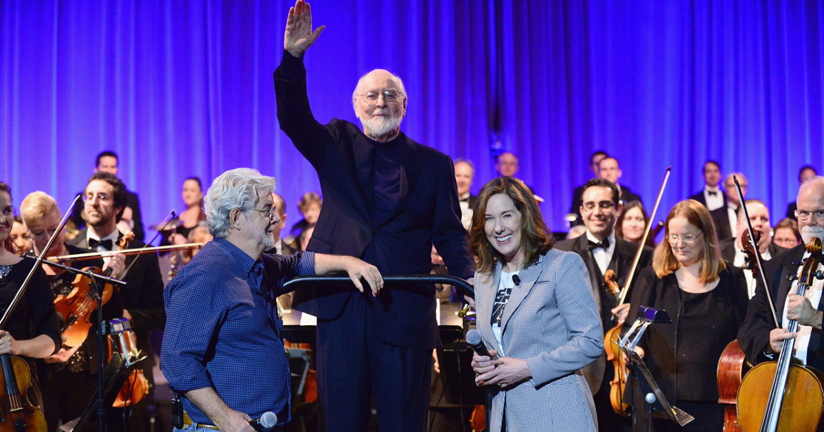 john williams saluta il pubblico davanti la sua orchestra e accanto c'è george lucas - nerdface