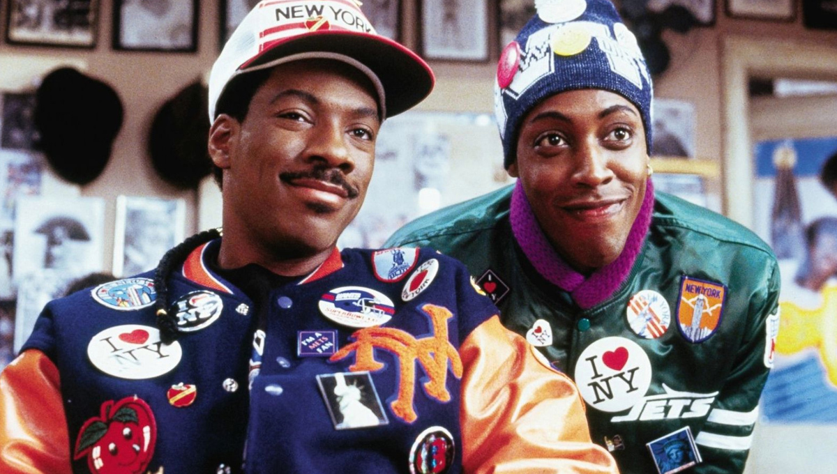 aresnio hall ed eddie murphy nel principe cerca moglie sono camuffati da abitanti del queens con giacche da baseball e spillette - nerdface