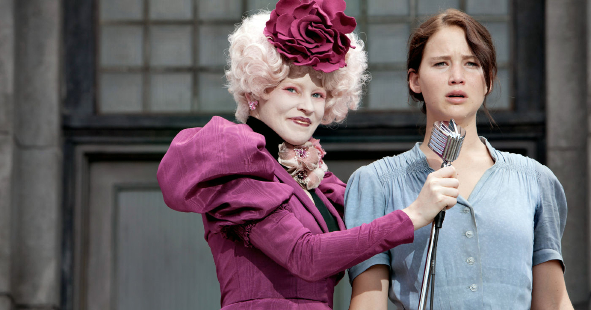 katniss si è appena sostituita alla sorella per gli hunger games e lo dice al microfono tenuto da una donna vestita in viola sgargiante - nerdface