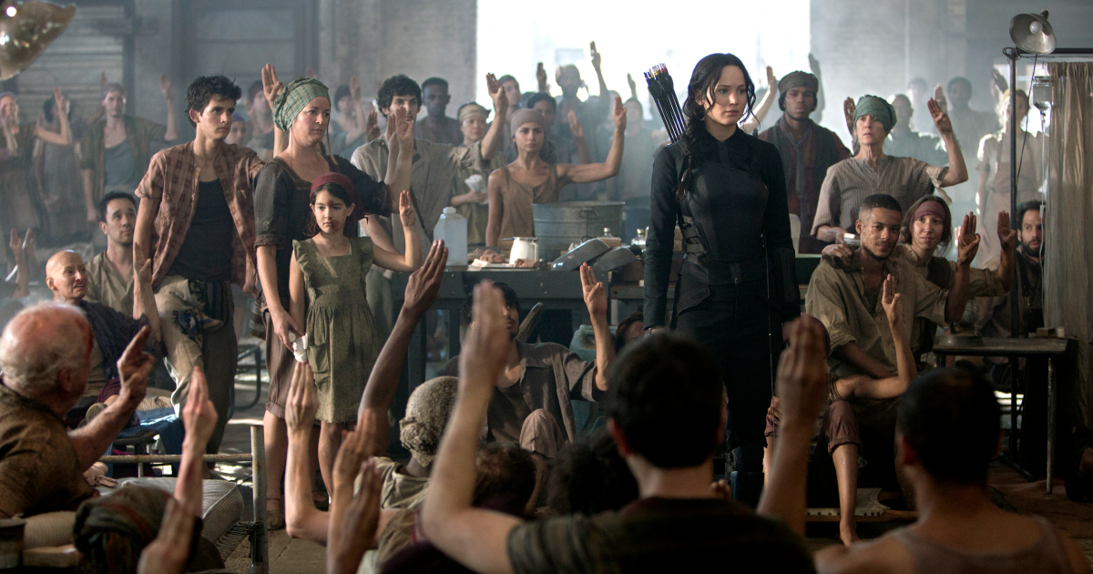 katniss è in una sala piena di poveracci che alzano la mano verso di lei - nerdface