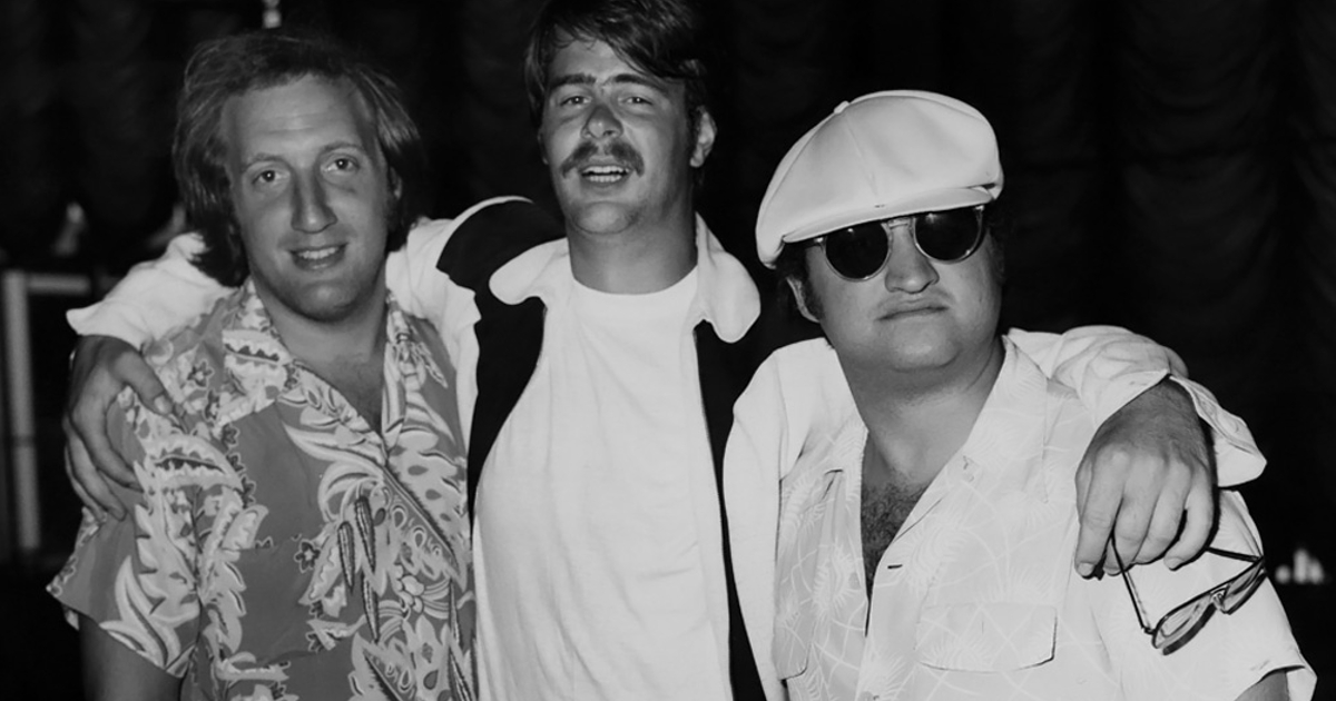 john belushi in bianco è abbracciato all'amico dan aykroyd e a uno scrittore - nerdface