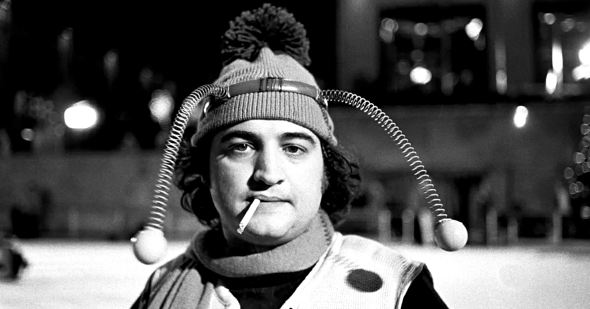 john belushi in animal house fuma una sigaretta e indossa un cerchietto con le molle - nerdface