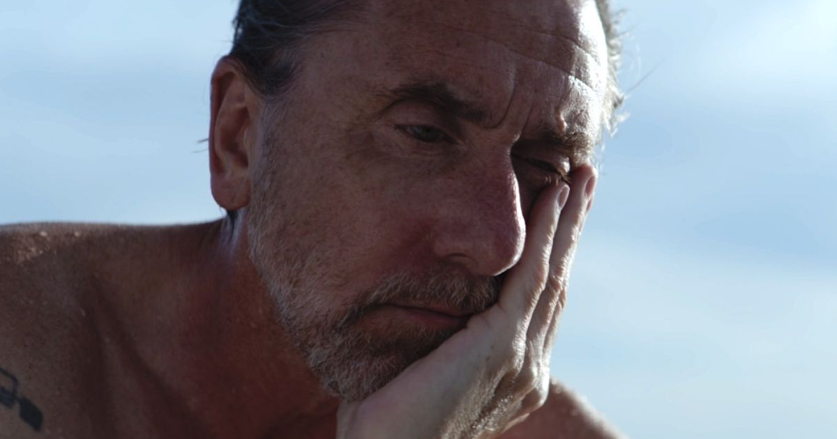 tim roth si tiene il mento e ha un'espressione molto malinconica in sundown - nerdface
