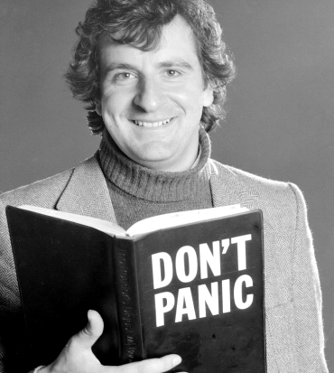 douglas adams tiene in mano un libro con scritto don't panic - nerdface