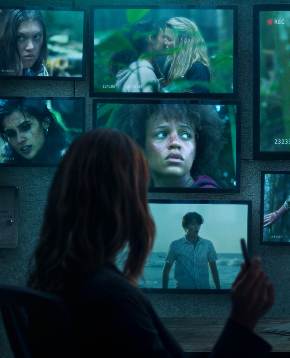 una donna osserva diversi schermi per spiare le ragazze naufraghe - nerdface