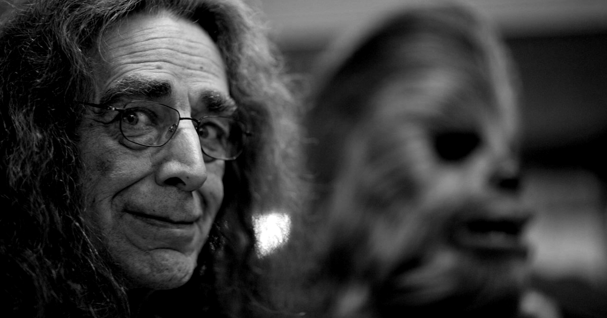 peter mayhew sorride e di fianco a lui c'è la maschera di chewbacca - nerdface