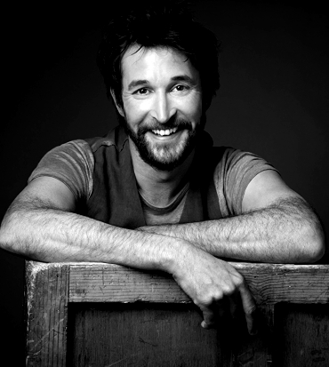 noah wyle sorride poggiato su una cassa di legno - nerdface