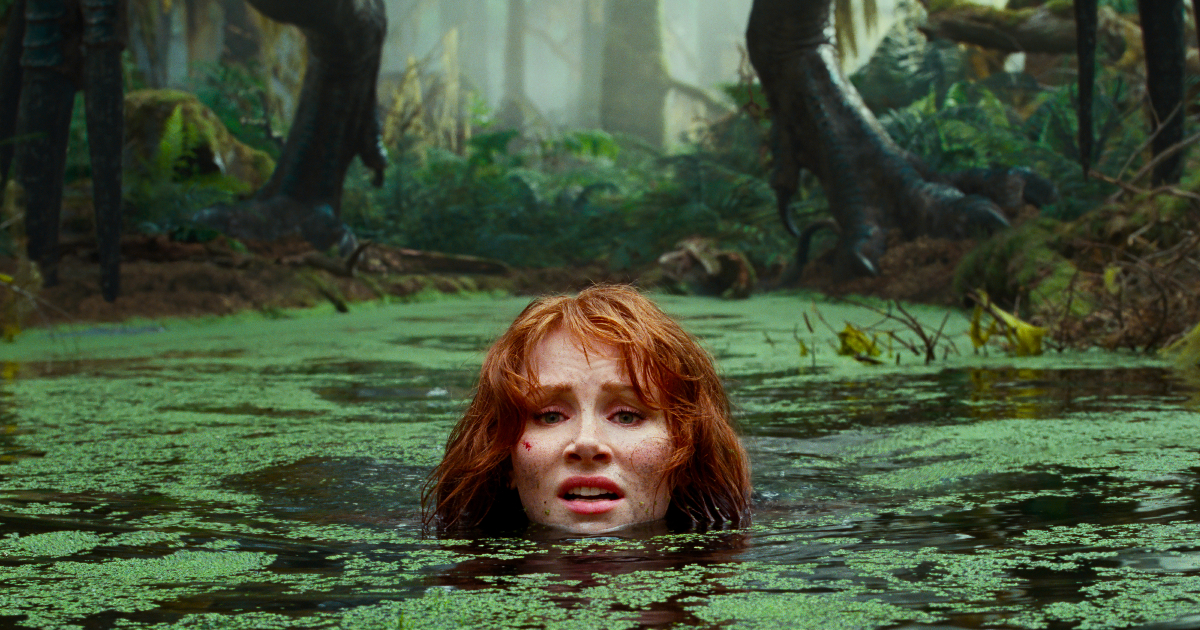 in jurassic world il dominio bryce dalla howard si immerge in una pozza per sfuggire a un dinosauro alle sue spalle - nerdface