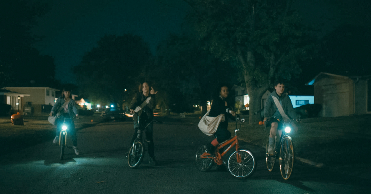 le protagoniste di paper girls sono in bicicletta, per strada, la sera - nerdface