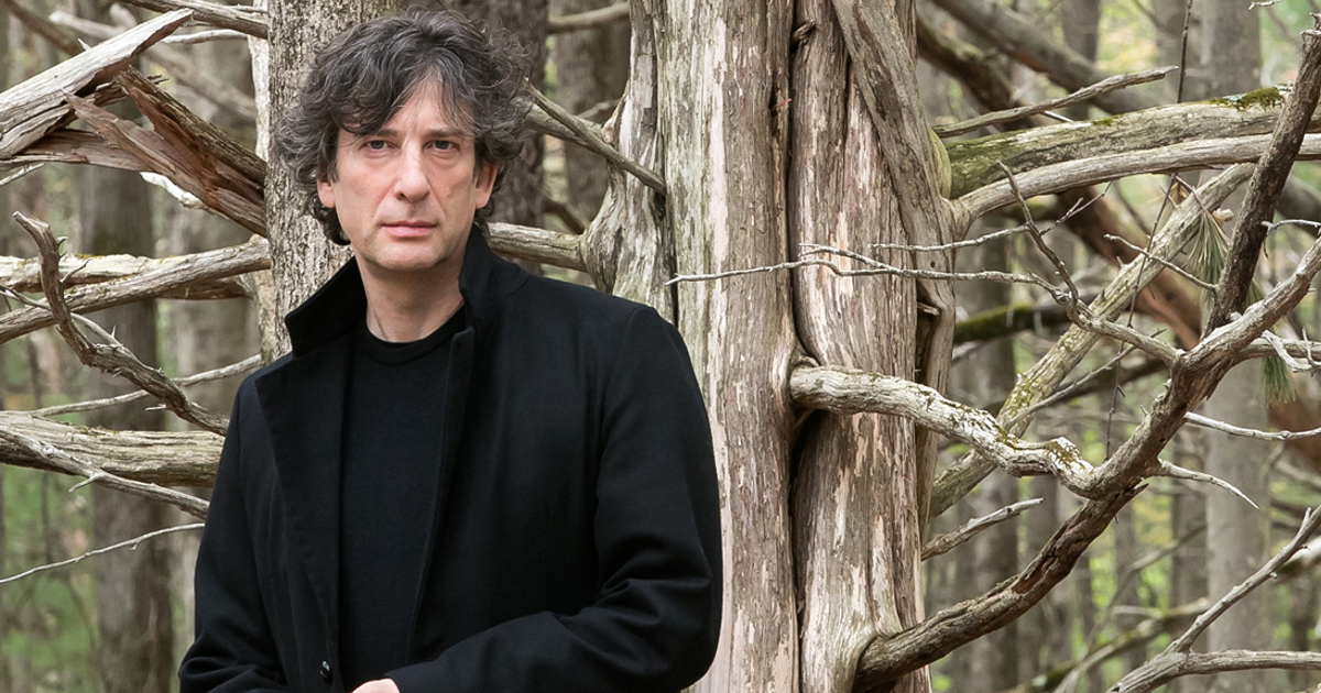 neil gaiman in posa davanti un albero secco - nerdface