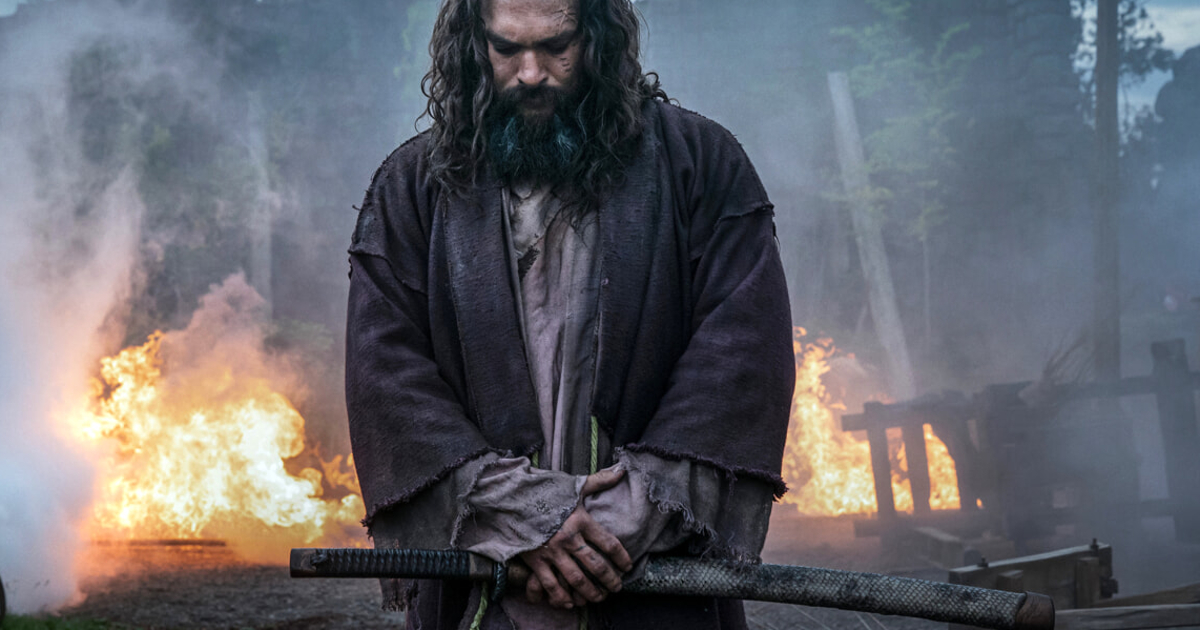 jason momoa medita mentre alle sue spalle brucia un villaggio nella terza stagione di see - nerdface