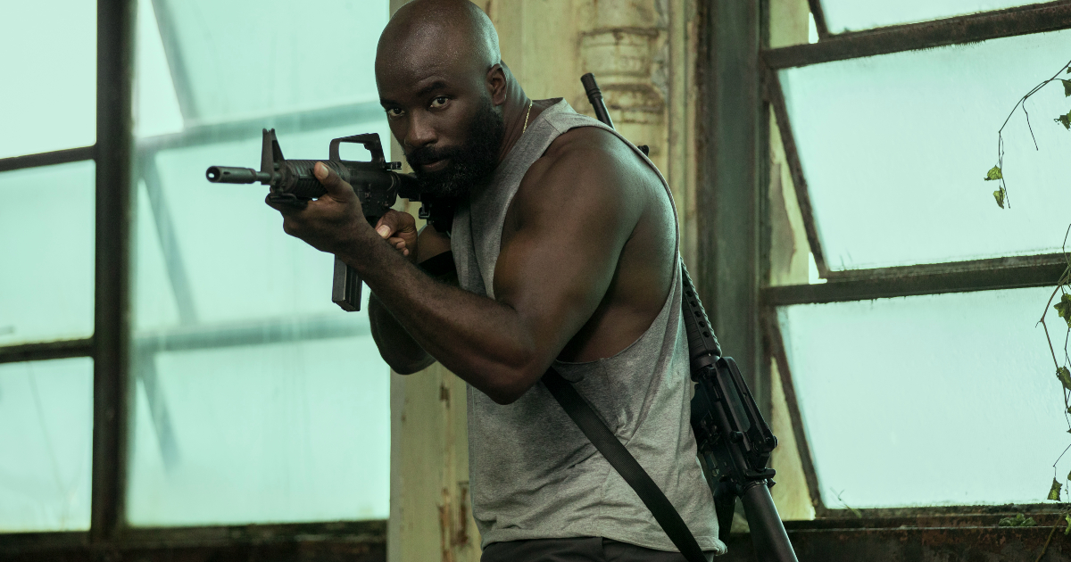 mike colter imbraccia un mitra in the plane - nerdface