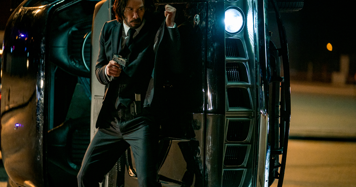 john wick si ripara dietro un'auto ribaltata - nerdface