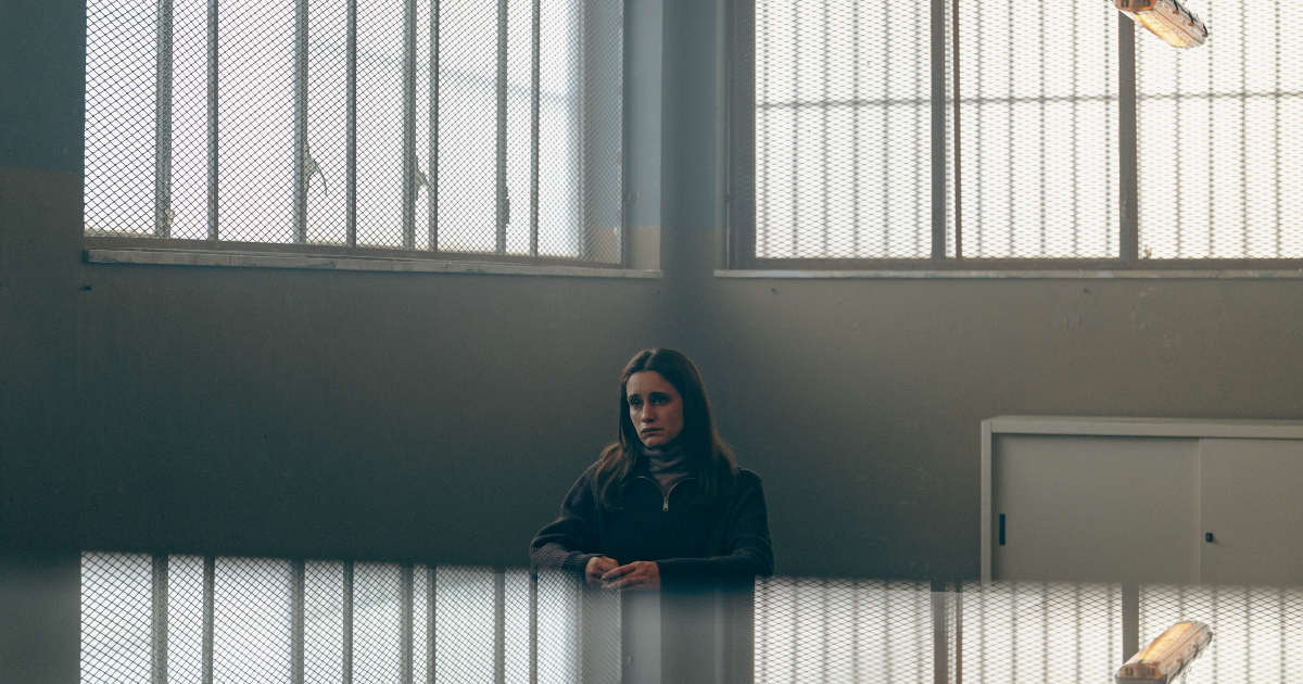 una donna è seduta in una sala vuota del carcere - nerdface