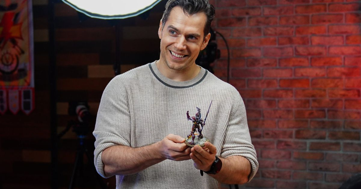 henry cavill tiene in mano felice una statuetta di warhammer - nerdface