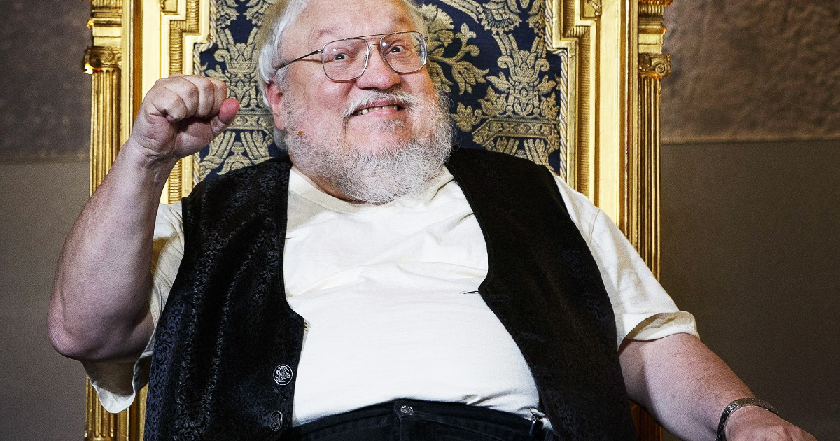 george r.r. martin fa il pugno chiuso seduto su uno scranno - nerdface