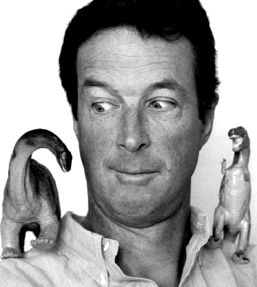 michael crichton osserva in modo buffo un pupazzo di dinosauro - nerdface