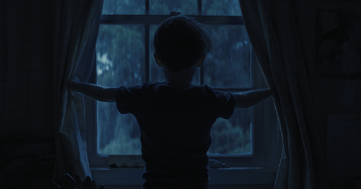 un bambino apre la tenda della finestra nella notte in weapons - nerdface