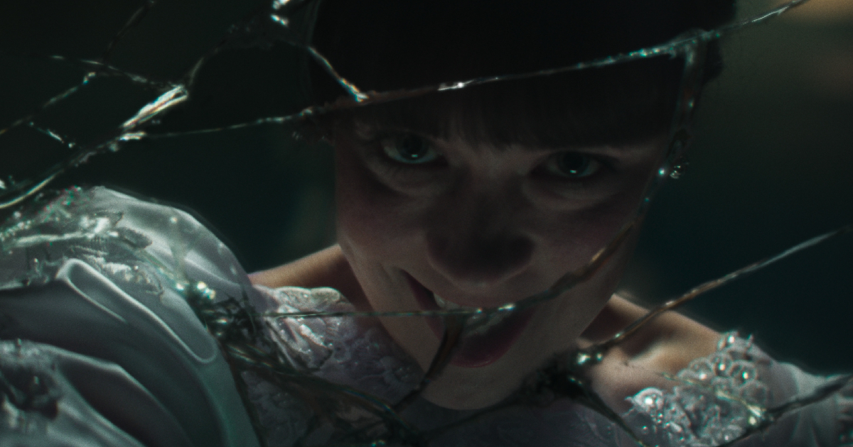 una ragazza demoniaca sorride riflessa su uno specchio scheggiato in the conjuring il rito finale - nerdface