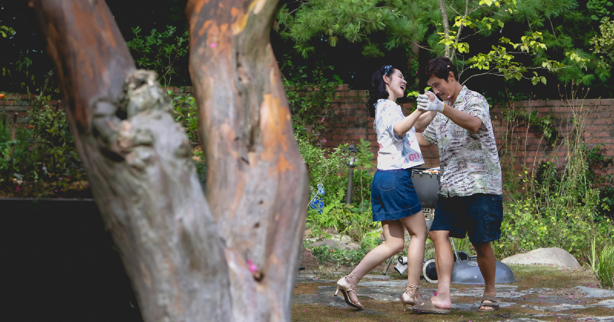 il protagonista di no other choice balla con la moglie in un giardino - nerdface