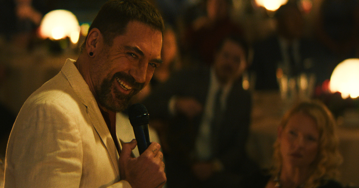 Javier Bardem in primo piano con un microfono in mano e un sorriso inquietante - nerdface