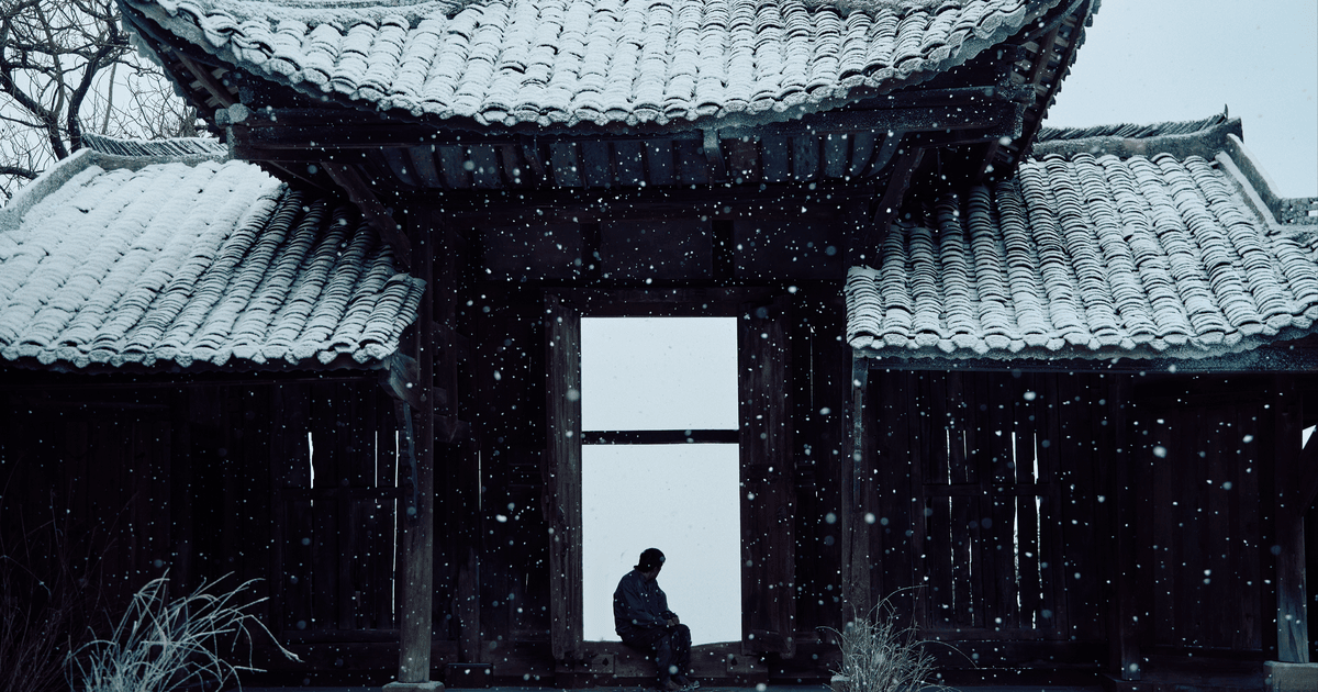 Un uomo seduto sull'uscio di un tempio giapponese innevato - nerdface